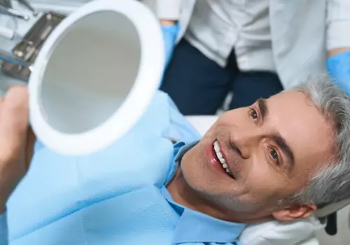 A man admiring his teeth and the work of a Cosmetic Dentist for Dunlap IL