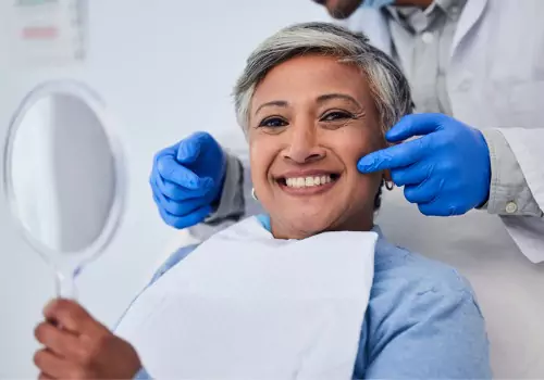 A Cosmetic Dentist near Dunlap IL pointing to a woman's recently treated teeth