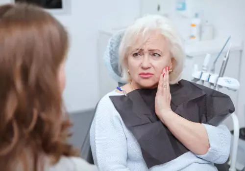 An elderly woman holding her mouth in pain, needing Family Dental Care in Pekin IL