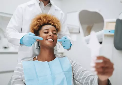 A woman smiles in the mirror after getting care from Total Dental Care, a Dental Clinic in Pekin IL
