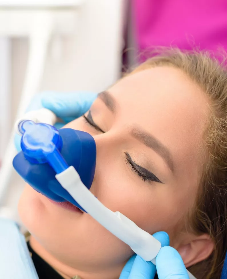 A woman uses inhalation sedation at Total Dental Care, which provides sedation dentistry as part of its dental services