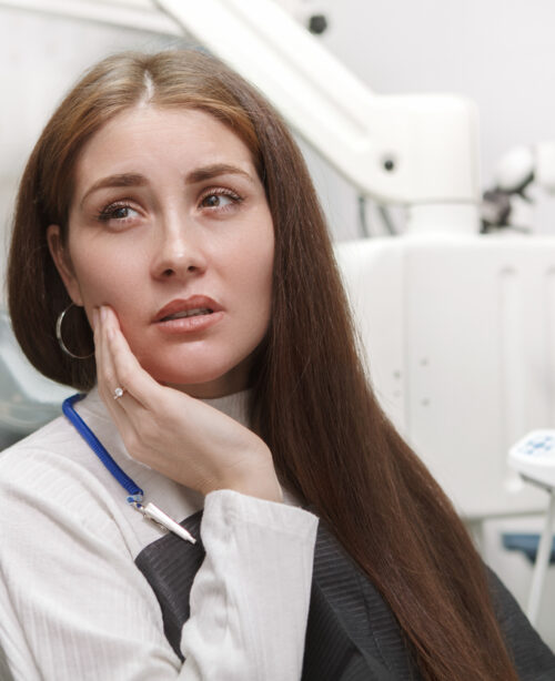 A patient with pain in her jaw sits through a consultation for dental emergencies