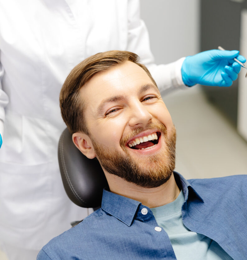A man sits smiling in a chair at Total Dental Care, which offers restorative dentistry and more